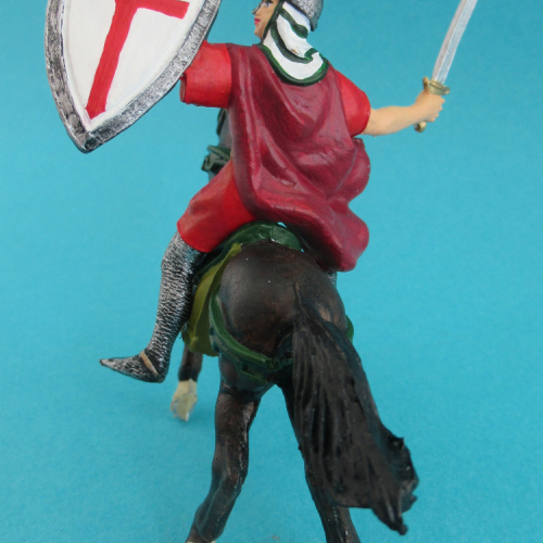 Cavalier croisé avec cape, épée et bouclier levés.