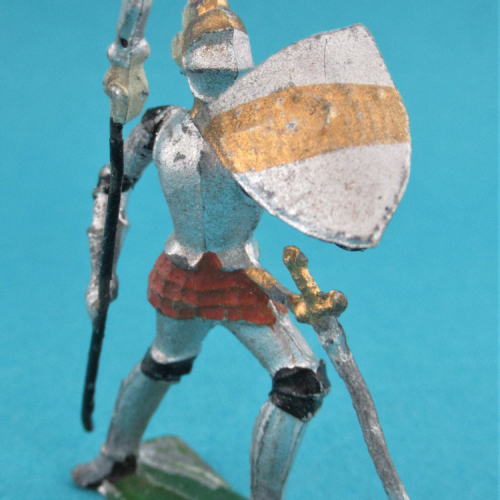 Chevalier au combat, casque à 3 plumets, visière fermé avec lance et écu barré.